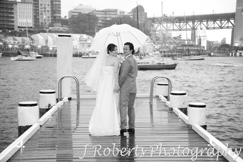 Bride and groom looking back over their shoulders under the umbrella - wedding photography sydney